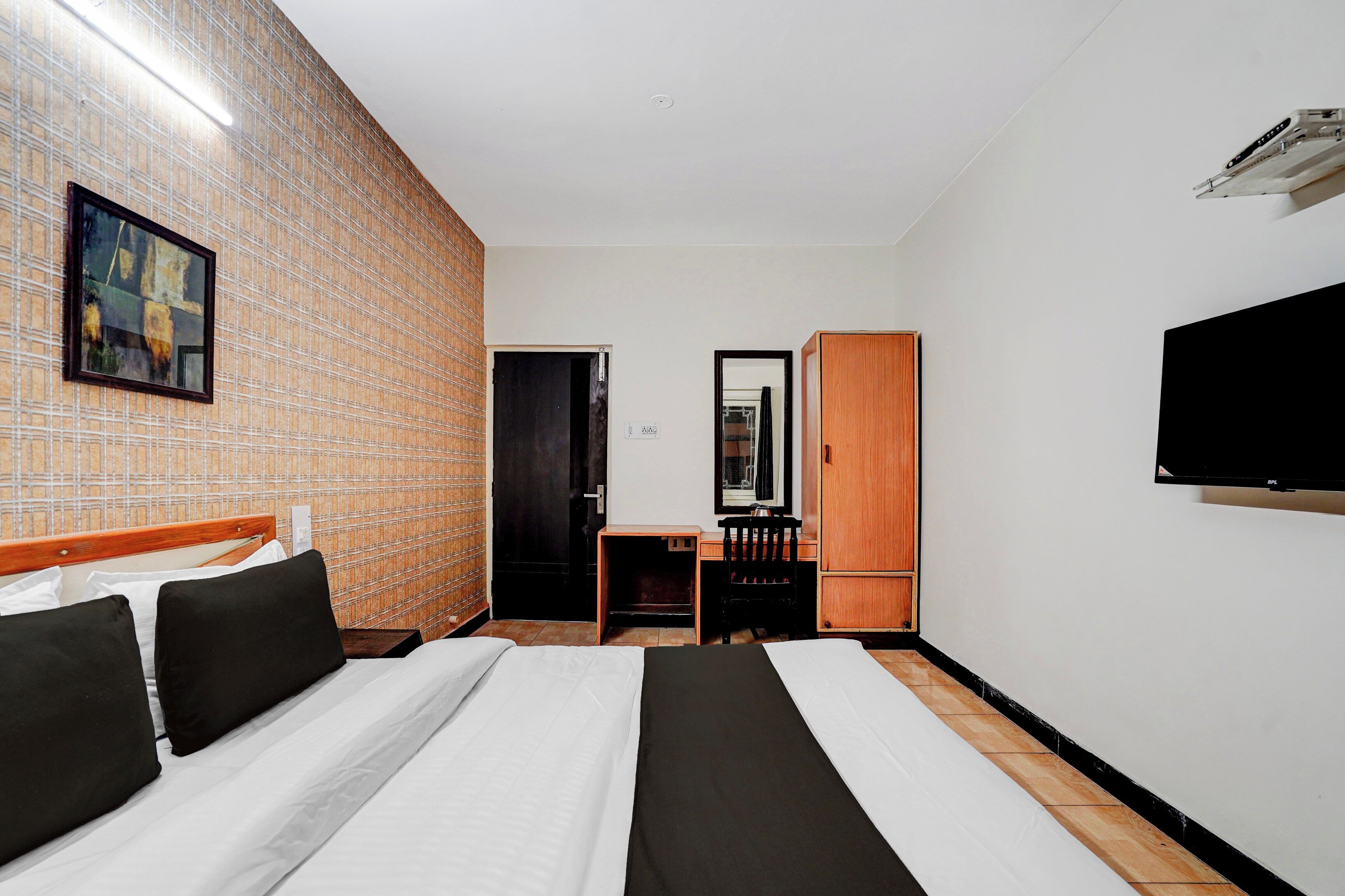 Una habitación de hotel con una cama, un escritorio, una silla, un armario y un televisor.