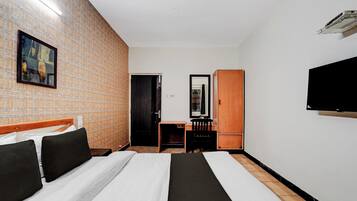 Una habitación de hotel con una cama, un escritorio, una silla, un armario y un televisor.