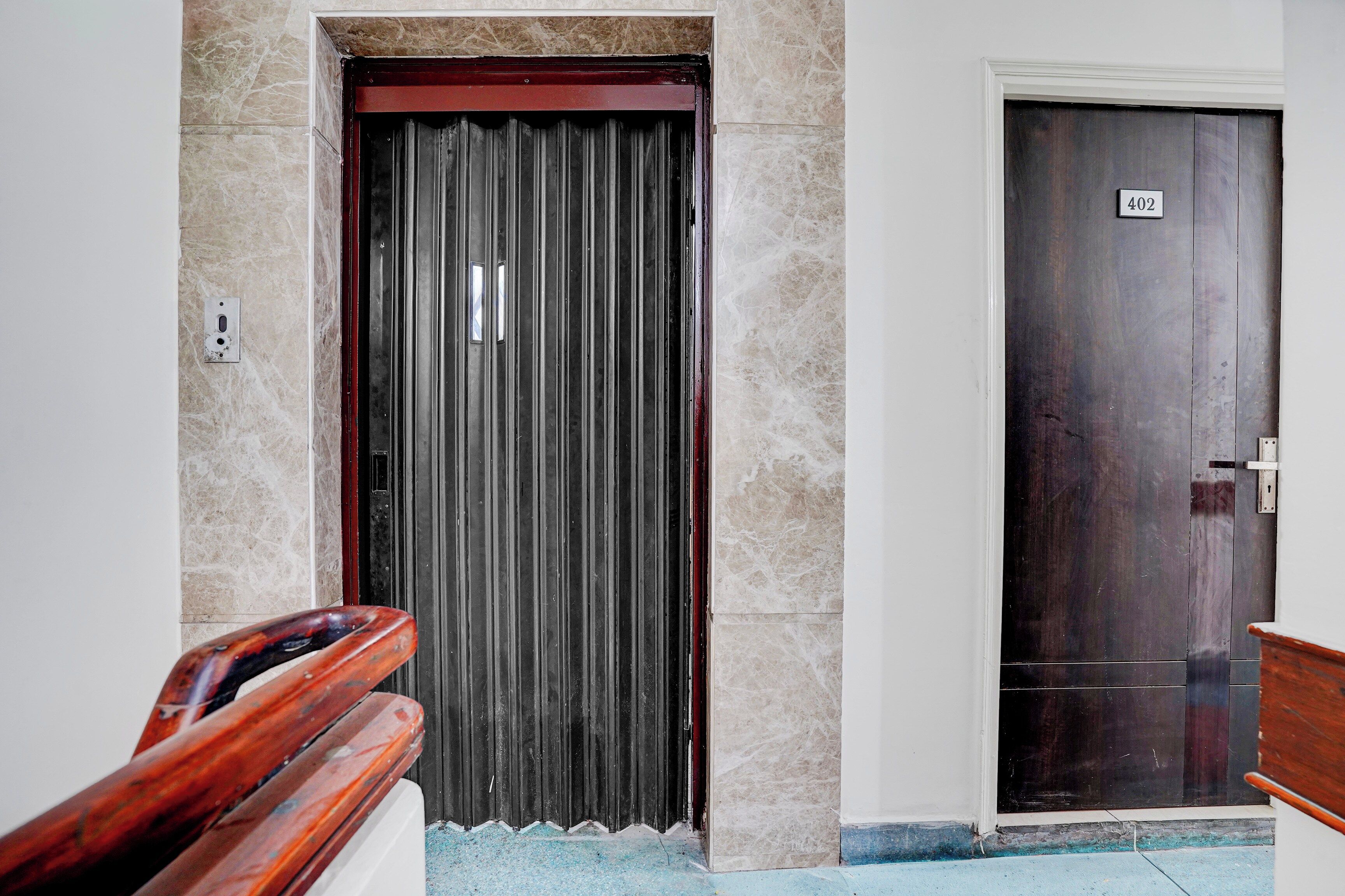 Entrada de hotel com porta de metal e porta de madeira indicada com o número 402.