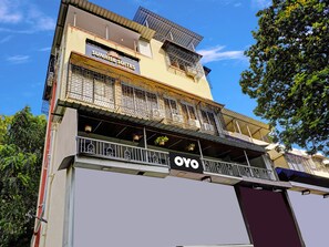 Un hotel con balcones, un cartel para Sunrise Suites y un cartel para OYO.