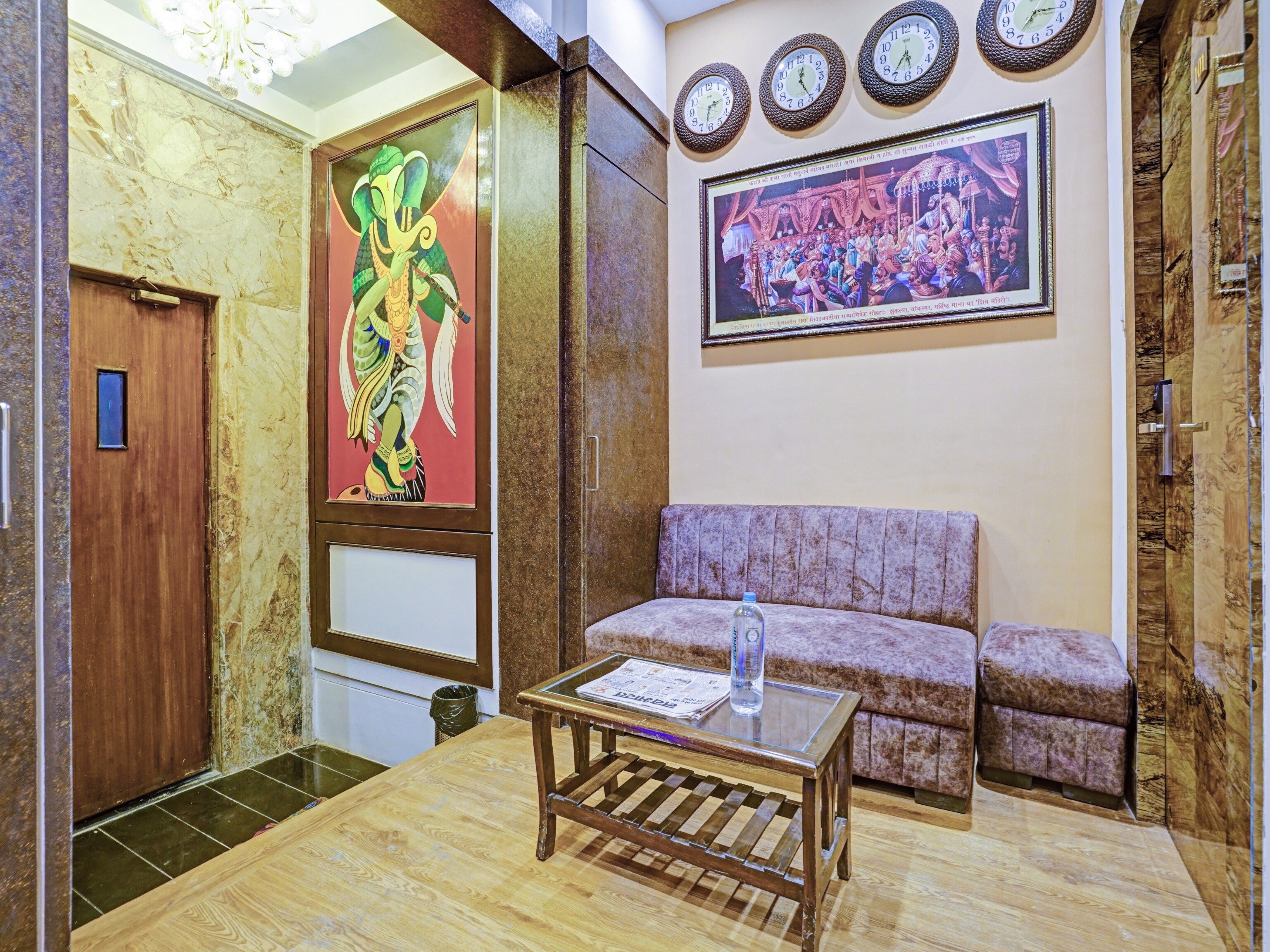 A lobby with a wooden table, a sofa, a painting of an elephant, and a clock on the wall.