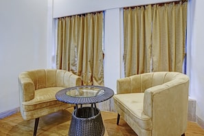 Una habitación con dos sillones, una mesita redonda y una cesta de mimbre.