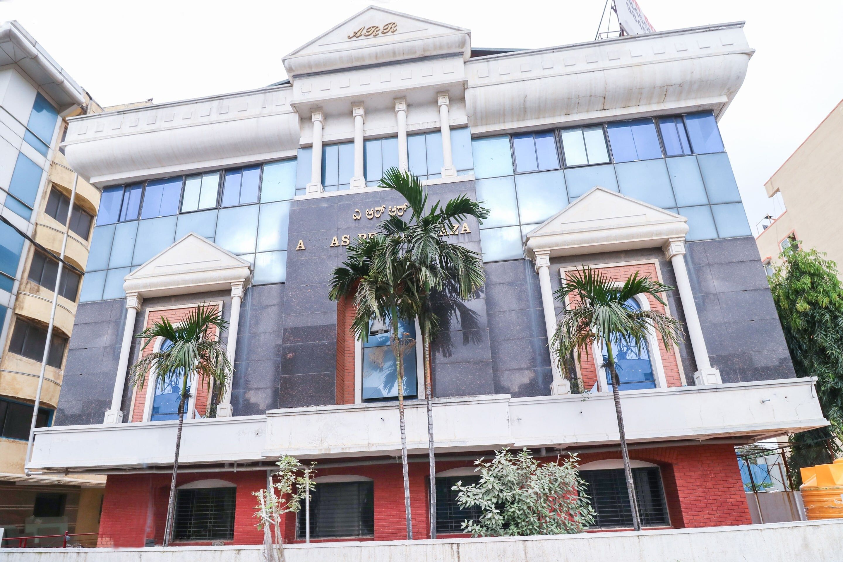 A multi-story building with a prominent sign reading 'AAS' and a large palm tree in front.