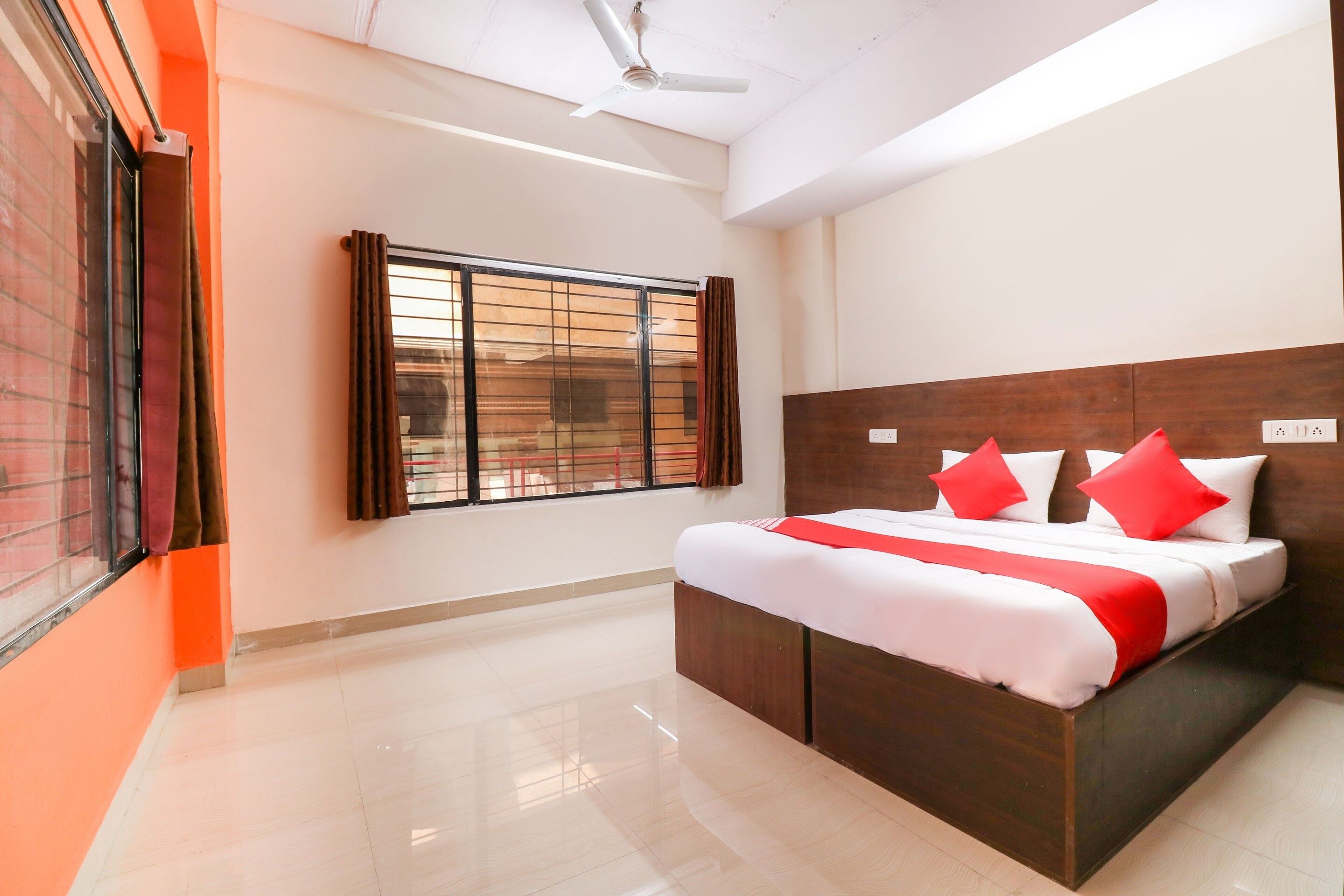 A hotel room with a large bed, a window with blinds, a ceiling fan, and a tiled floor.