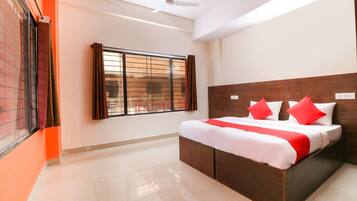 A hotel room with a large bed, a window with blinds, a ceiling fan, and a tiled floor.