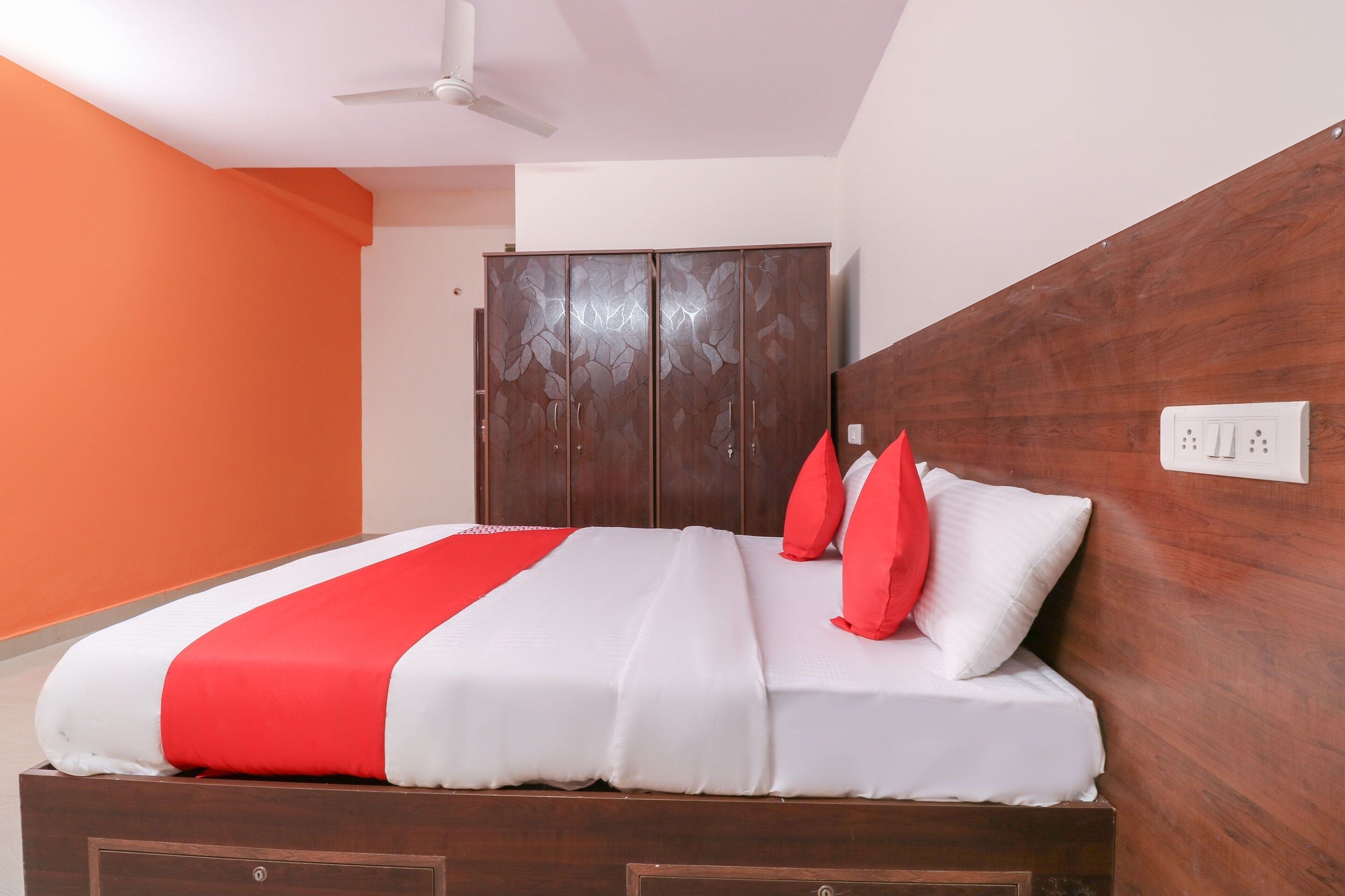 A hotel room with a bed, a wardrobe, and a ceiling fan.