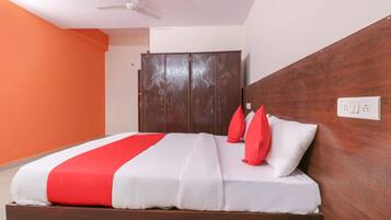 A hotel room with a bed, a wardrobe, and a ceiling fan.