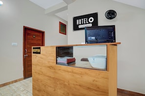 En receptionsdisk med träpanel, en skylt med texten ”Reception”, en väggmonterad fläkt och en dörr med nummerlappen ”101”.