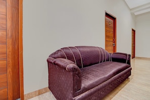 Una habitación con piso de madera, un sofá de cuero marrón y dos puertas de madera.