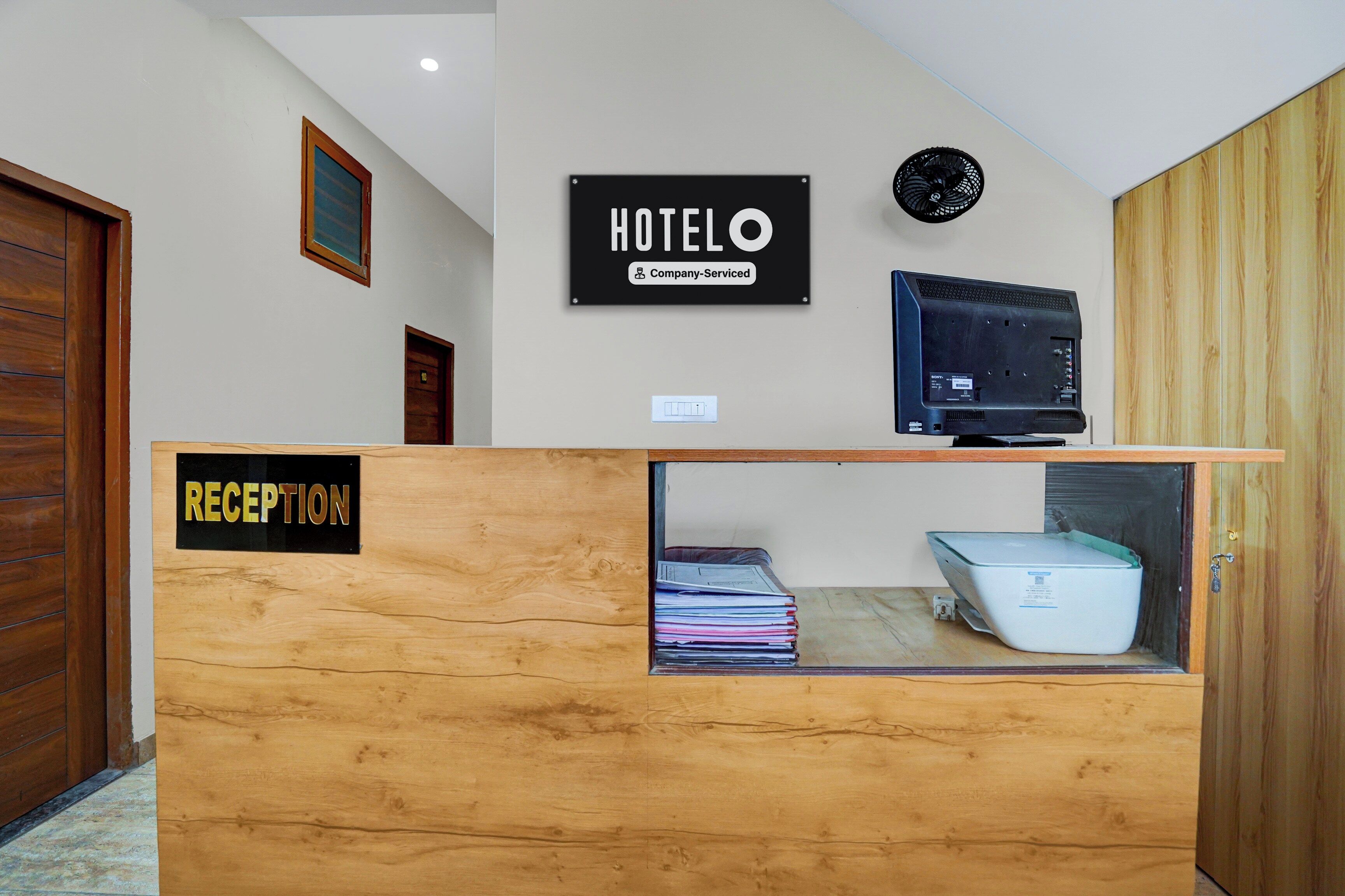 Un mostrador de recepción con un cartel que dice 'RECEPTION', un cartel que dice 'HOTEL' y un televisor Sony montado en la pared.