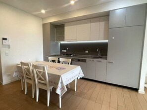 A compact kitchen with a dining table and chairs, a built-in oven, and a dishwasher. - Stylish Modern Retreat in Ermington (Ermington)