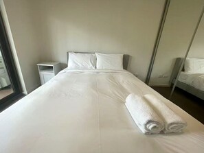 A hotel room with a large bed, a nightstand, a mirror, and a window. - Stylish Modern Retreat in Ermington (Ermington)