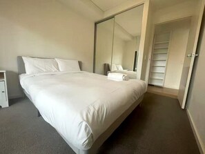 A hotel room with a large bed, a wardrobe, a mirror, and a door leading to a closet. - Stylish Modern Retreat in Ermington (Ermington)