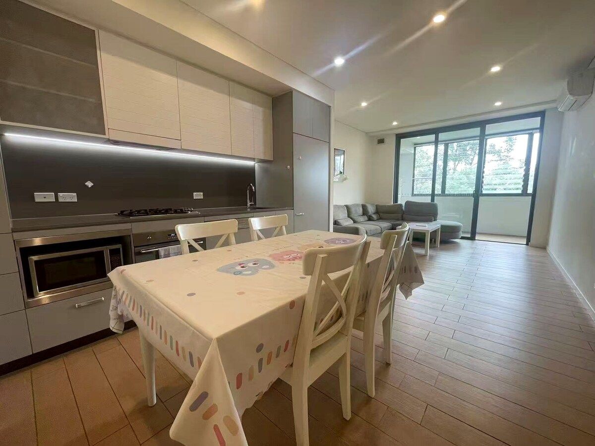 A modern kitchen with built-in appliances and a dining area with a table and chairs.