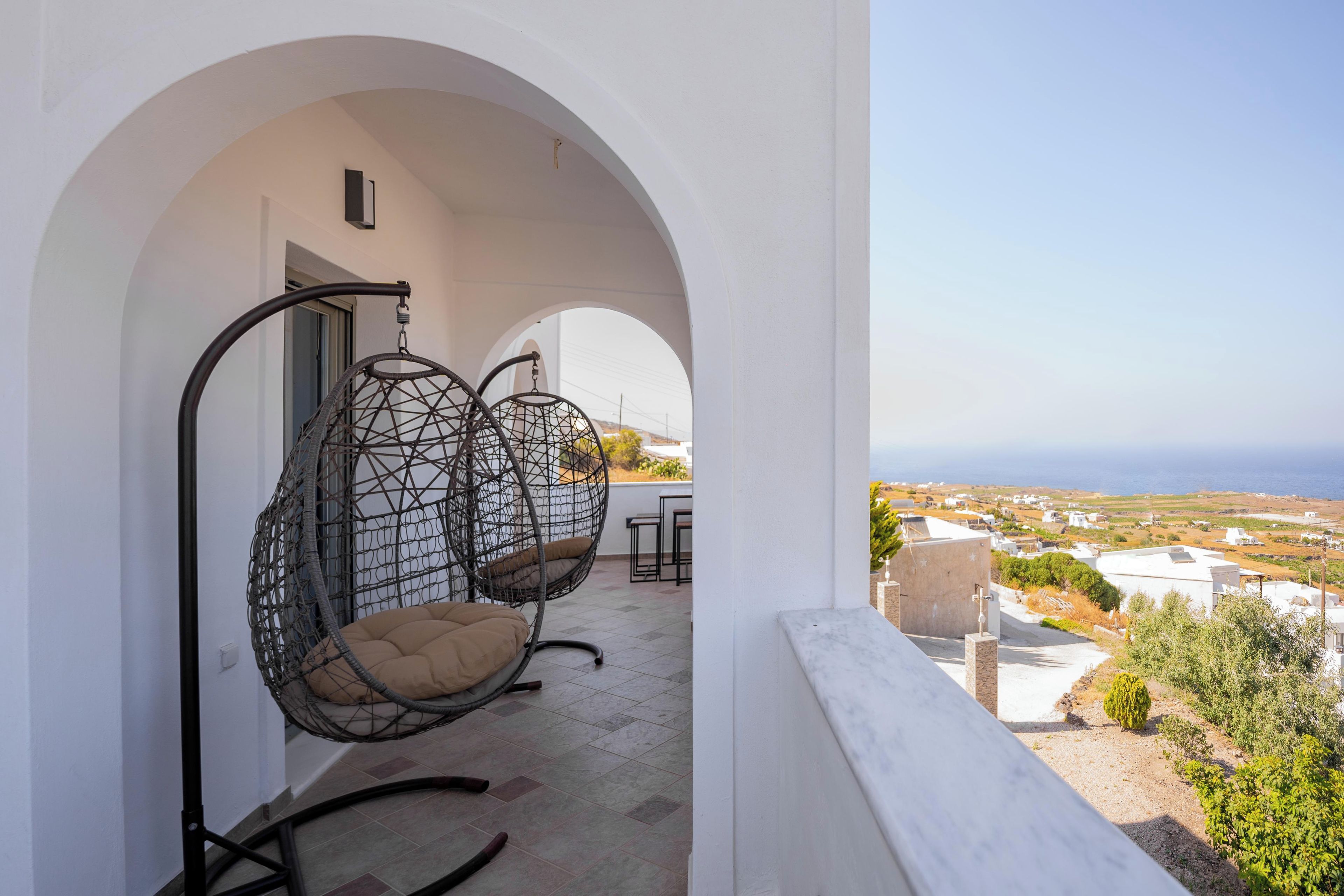 A balcony with two hanging chairs and a view of the sea.