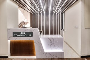 A reception area with a marble counter, a sign reading 'OYO TOWNHOUSE', and a staircase in the background.