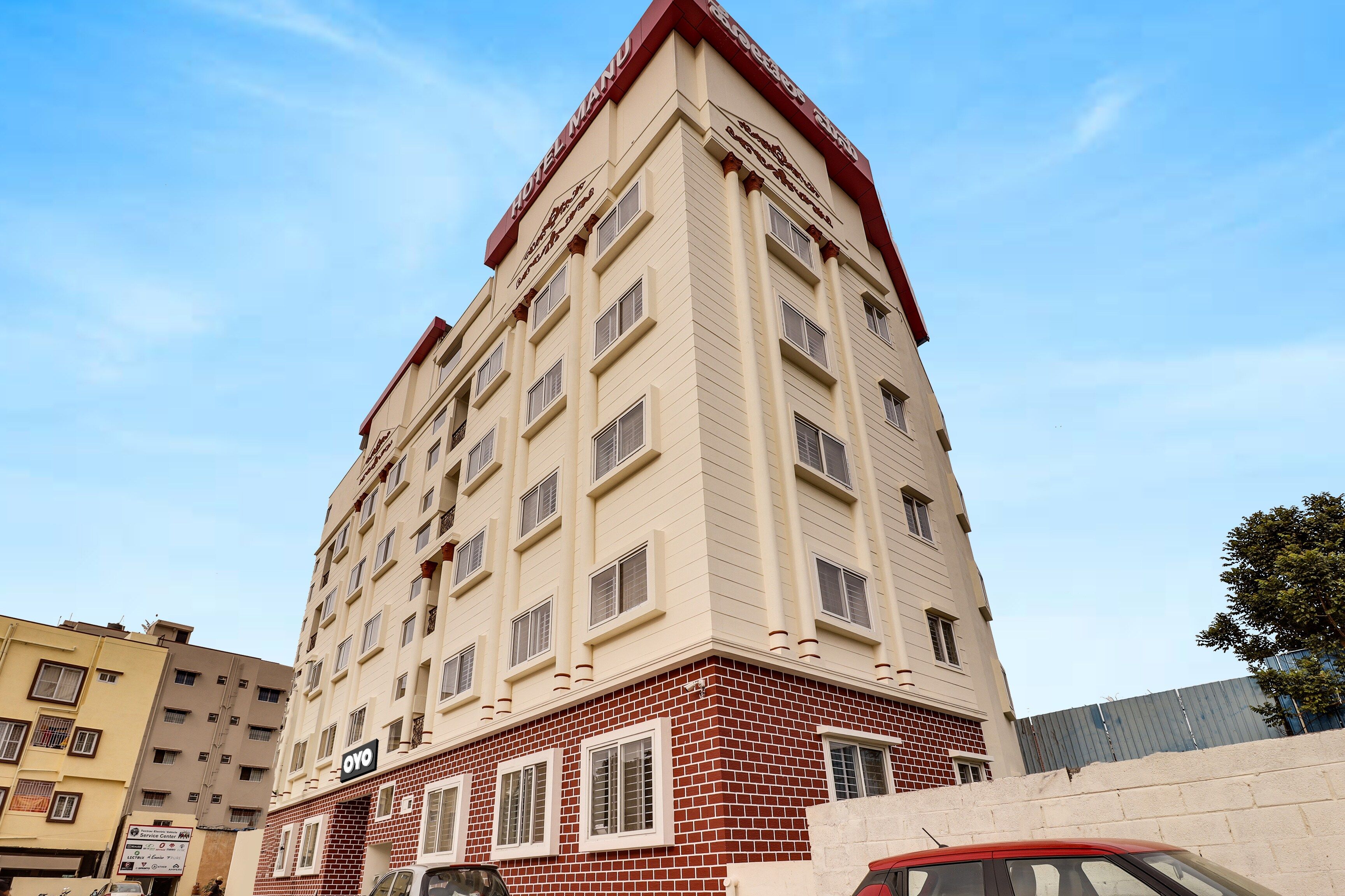 Un edificio de hotel de varios pisos con fachada roja y color crema, numerosas ventanas y un letrero de centro de servicios visible.