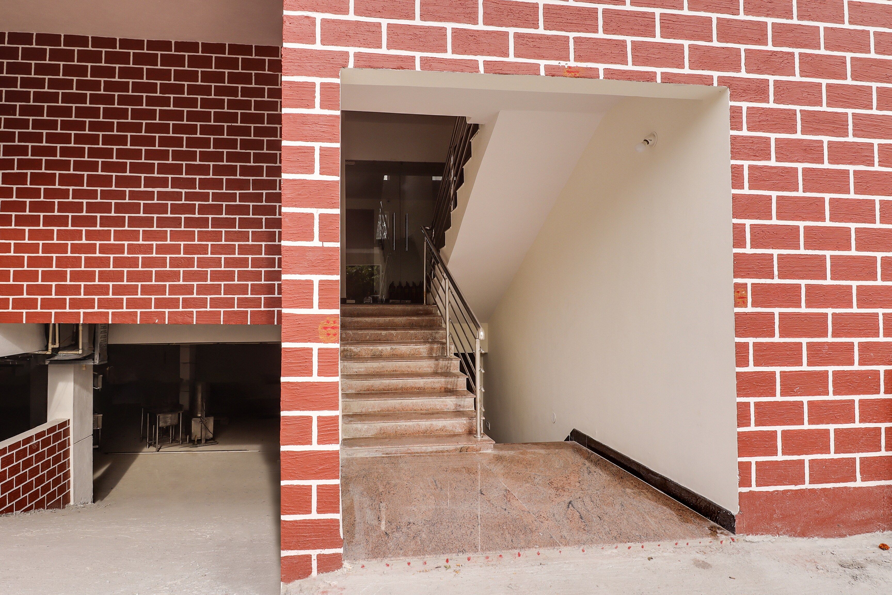 Una escalera conduce a una plataforma con un muro de ladrillo a un lado y una pared blanca al otro.