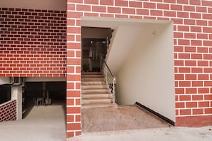 A staircase leading to a landing with a brick wall on one side and a white wall on the other.