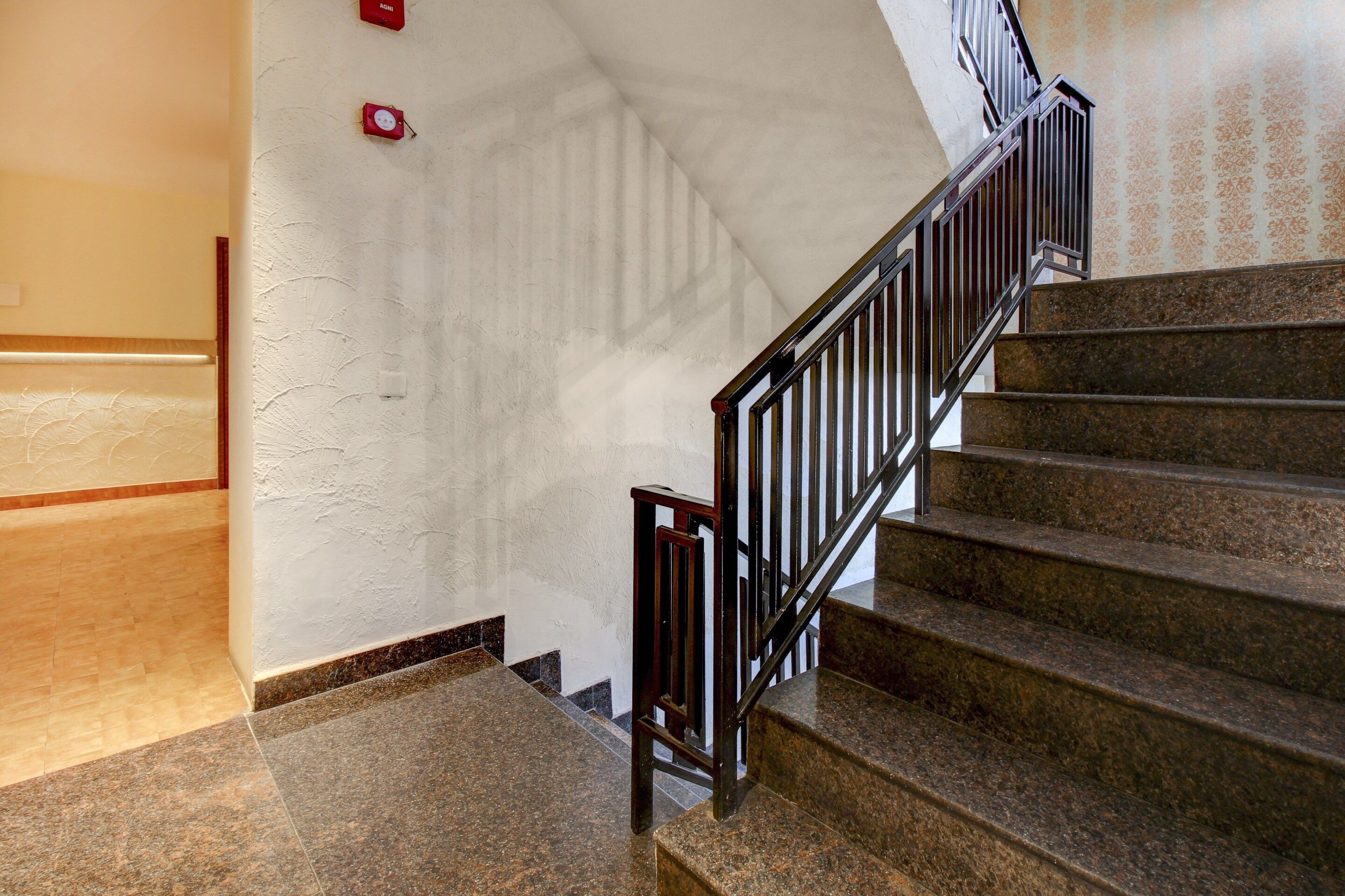 A staircase with a handrail, carpeted steps, and a wall with a textured finish.