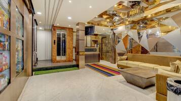 A modern lobby with a reception desk, a sofa, a coffee table, and a patterned rug.