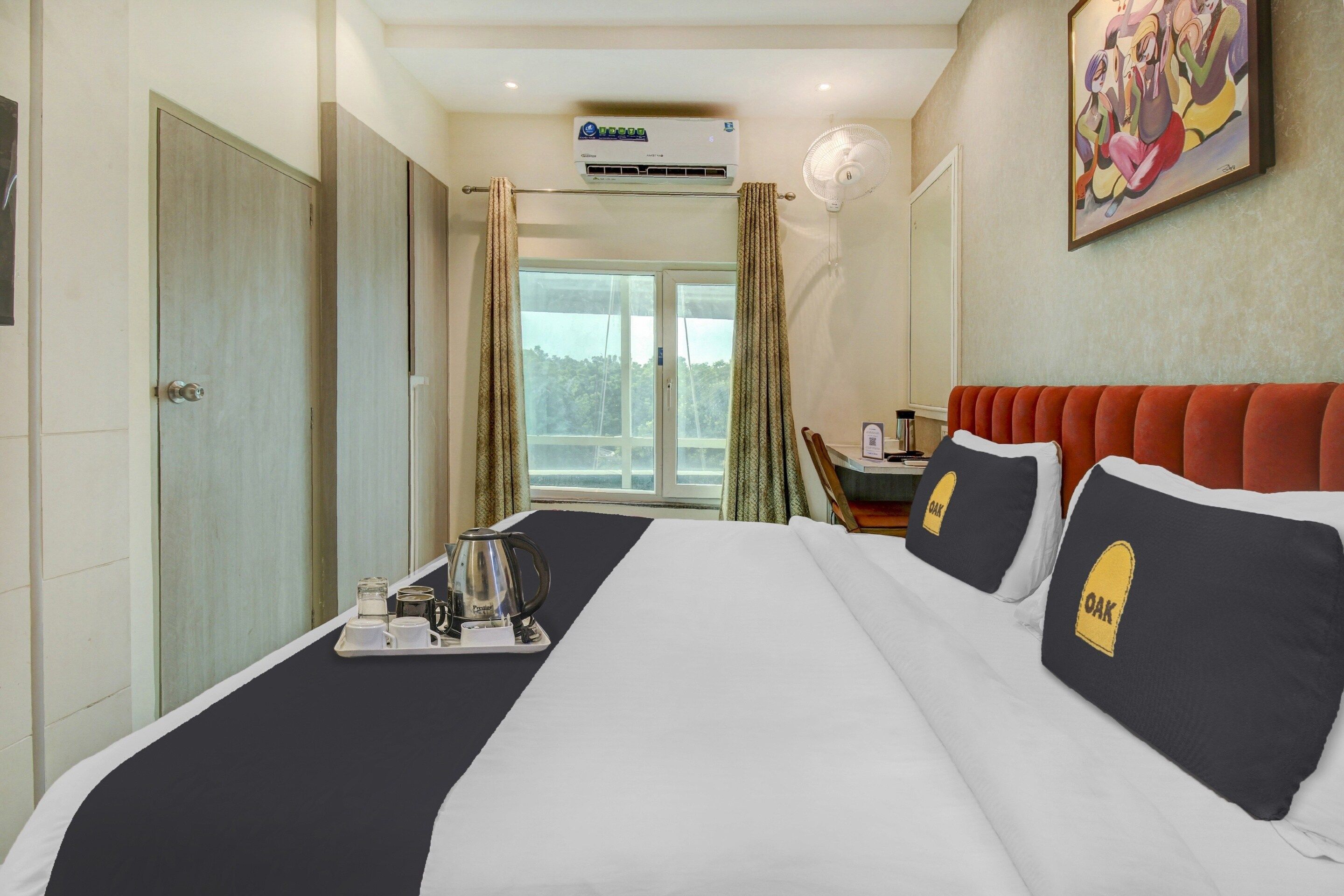 Habitación de hotel con cama, escritorio, ventana y equipo de aire acondicionado.