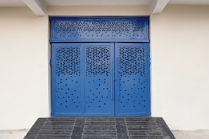 Una puerta azul con patrones geométricos y flechas, sobre un fondo de pared lisa.