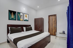 Una habitación de hotel con cama, armario y obras de arte en la pared.