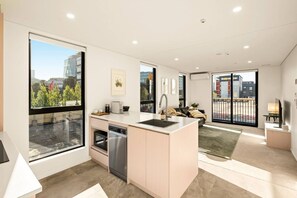 A modern kitchen with a central island, built-in appliances, and large windows offering a city view. - Beautifully Furnished 1-Bed in the City Centre (Christchurch)