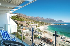 Ein Balkon mit Blick auf eine Küstenstadt, einen Strand und Berge in der Ferne.