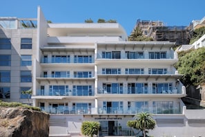 A multi-story building with a modern architectural design, featuring balconies with glass railings and a sign indicating 'DUNMORE APARTMENTS'. - Clifton 2 Bed Apartment Ocean Views Dunmore Noir (Cape Town)