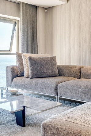 Ein modernes Wohnzimmer mit einer Eckcouch, einem Glastisch und Meerblick.