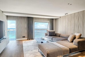 A modern living room with a large window, a sofa set, a coffee table, and a flat-screen TV. - Clifton 2 Bed Apartment Ocean Views Dunmore Noir (Cape Town)