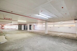 Eine Parkgarage mit Betonböden, weißen Wänden und roten Rohren.