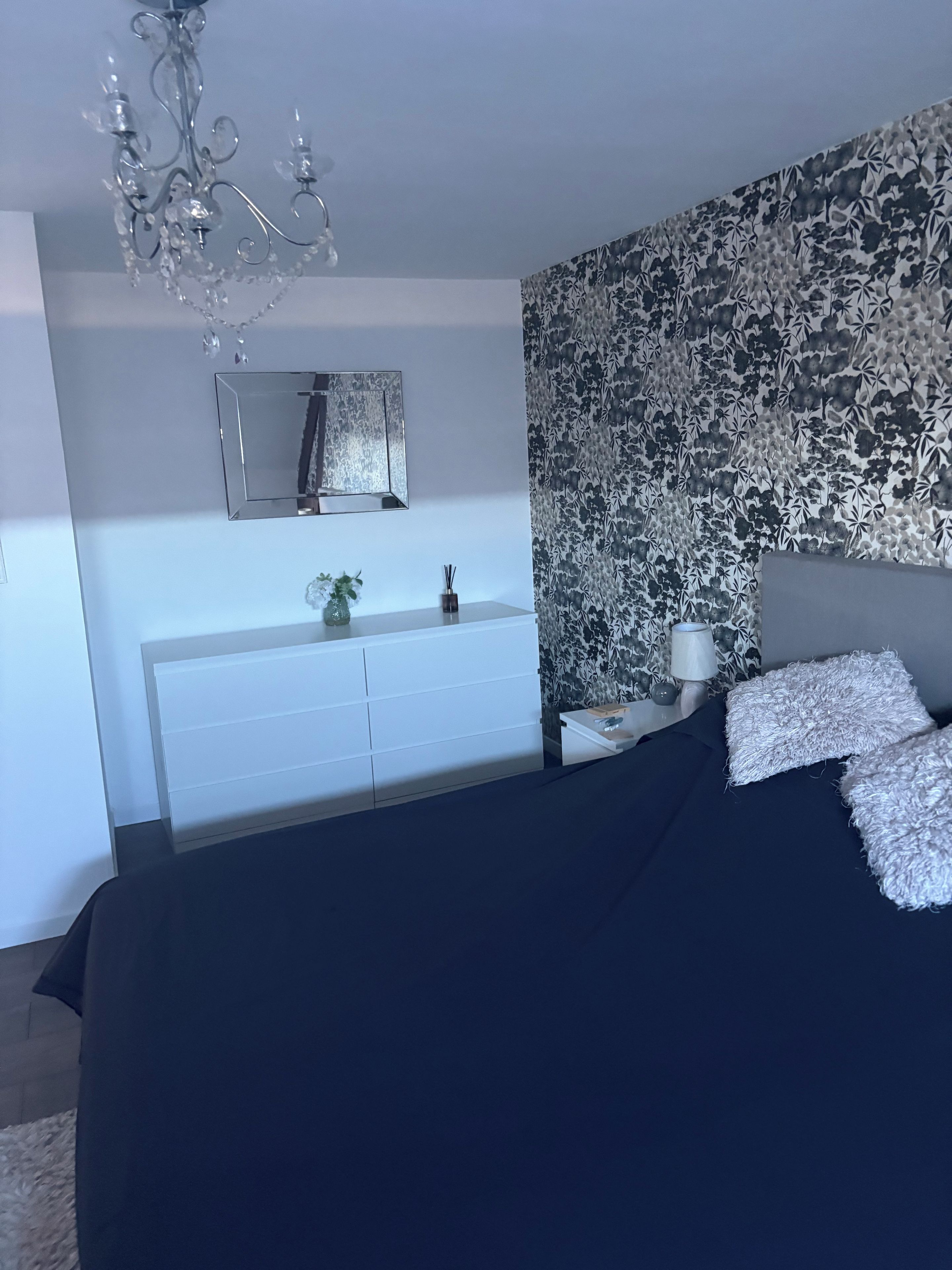 Ein Schlafzimmer mit einem Bett, einem Schminktisch, einem Spiegel und einer Kandelaber.