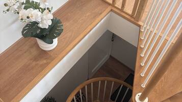 A wooden staircase with a white wall and a potted orchid plant.