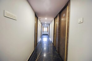 Un pasillo con puertas a ambos lados, suelo de color claro e iluminación empotrada en el techo.
