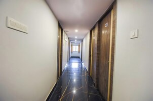 A corridor with doors on both sides, a light-colored floor, and a ceiling with recessed lighting.
