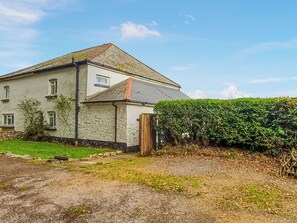 A two-story house with a sloped roof, a visible chimney, and a well-maintained hedge. - South Nethercott Farm Annexe (Okehampton - Whiddon Down)