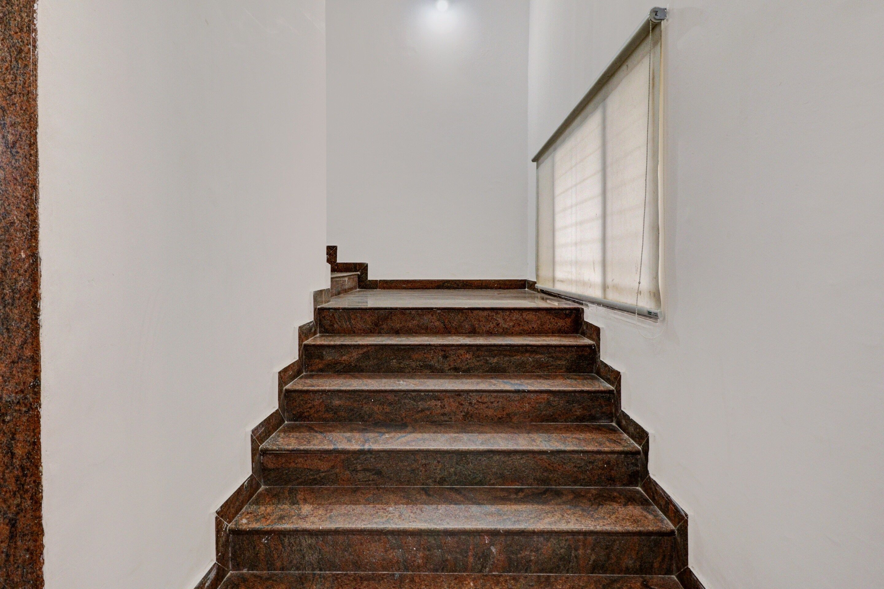 Una escalera con barandilla y una ventana con persianas.