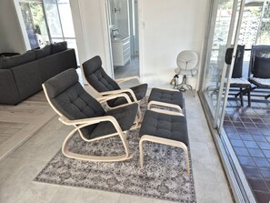 A modern living room with a grey sofa, a patterned rug, and a seating area with grey upholstered chairs and a wooden coffee table. - Spacious home 'Breeze on Prince', offers modern connectivity and luxury comfort. (Waratah)