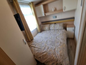 A compact bedroom with a bed, a bedside table, and a wardrobe. - Greenacres Holiday Park - Holiday Accommodation 20263 (Porthmadog)
