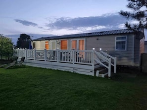 A single-story house with a covered porch, a staircase leading to the entrance, and a small front yard. - Greenacres Holiday Park - Holiday Accommodation 20263 (Porthmadog)