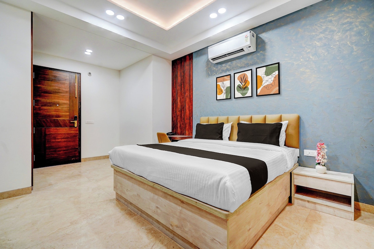 A modern bedroom with a wooden bed, a nightstand, an air conditioning unit, and framed artwork on the wall.