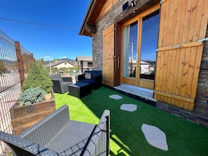 Una casa de madera con un patio, mobiliario exterior y vistas del entorno.
