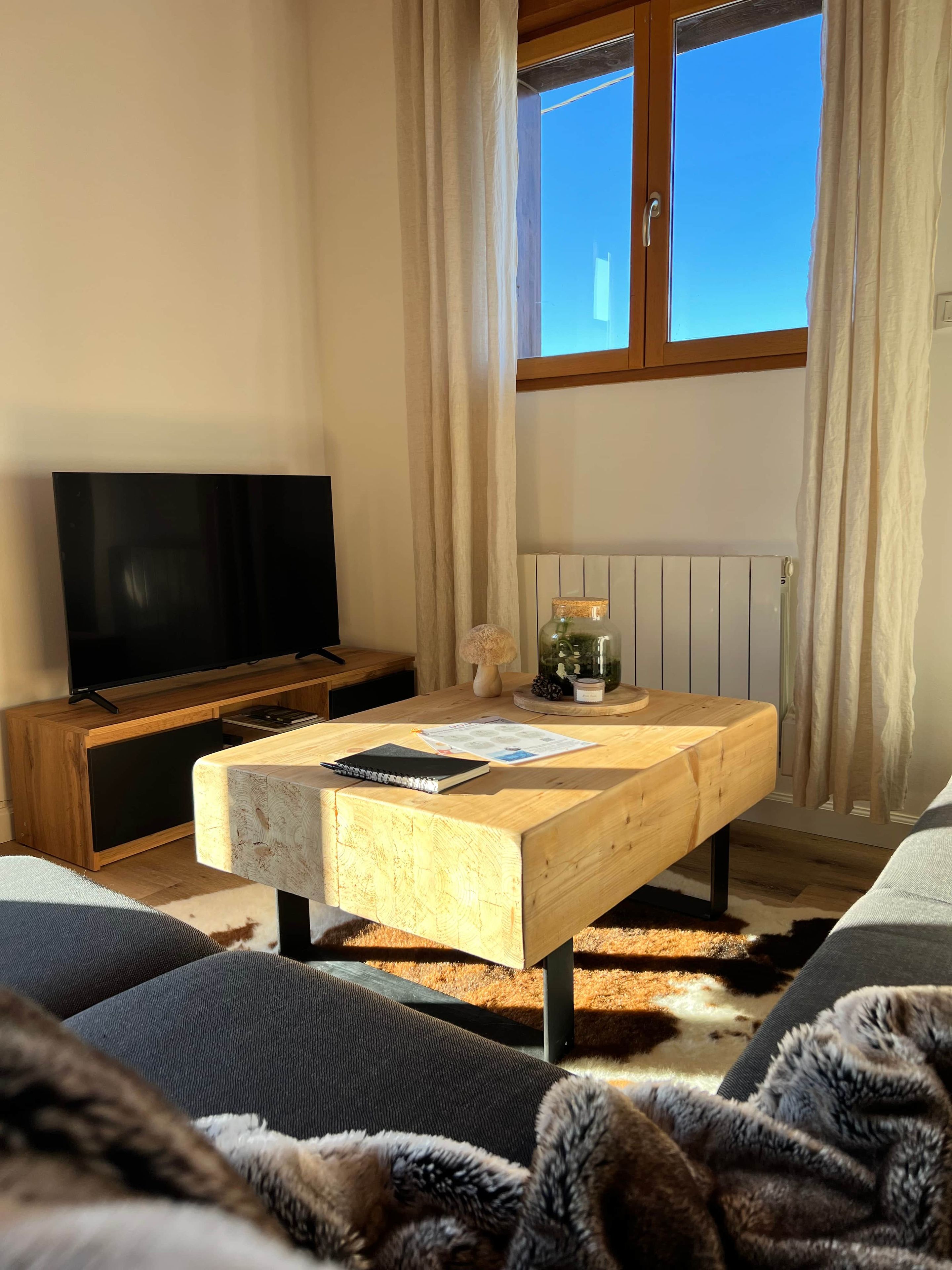 Ett modernt vardagsrum med ett soffbord i trä, en platt-TV och en bekväm soffa.