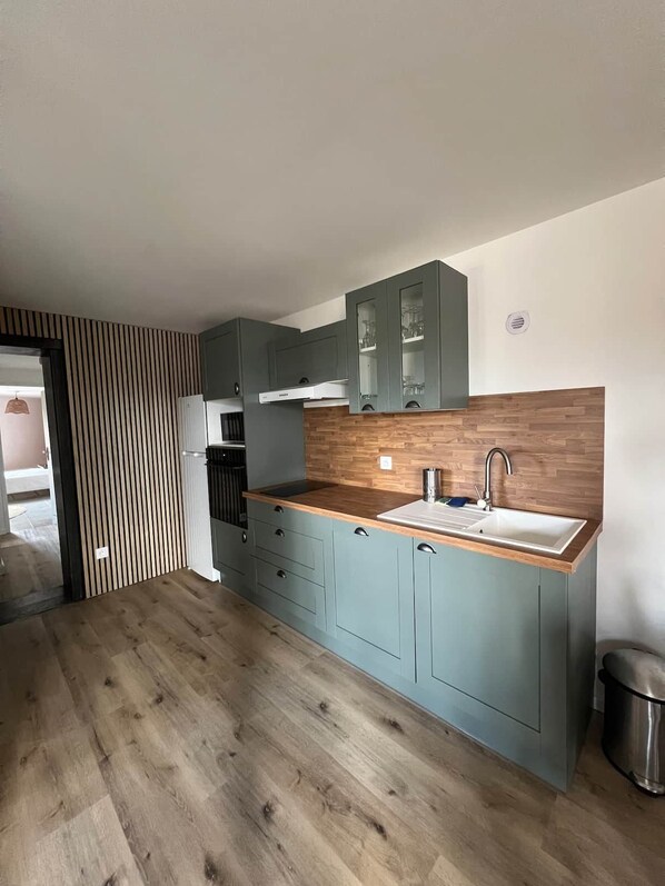 A modern kitchen with a wooden countertop, grey cabinets, and a stainless steel sink.