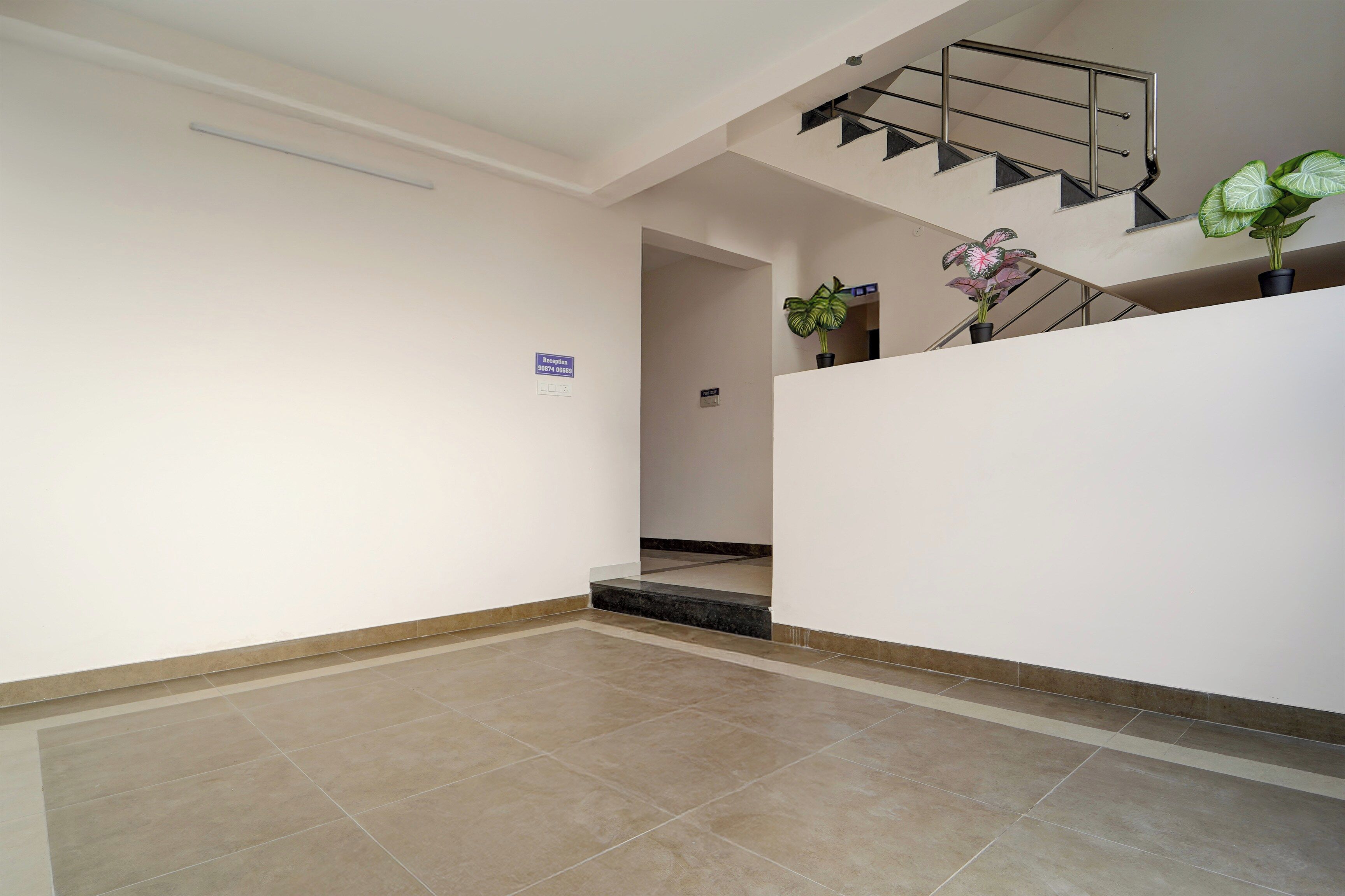 A reception area with a reception desk, a staircase, and a potted plant.