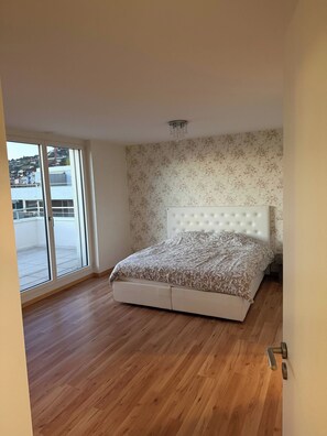 A bedroom with a large bed, a sliding glass door to a balcony, and a floral wallpaper. - A View to Remember VD (Montreux)