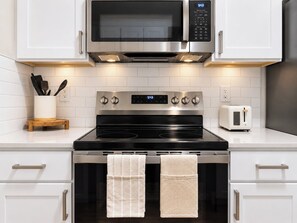 A modern kitchen with a stainless steel microwave, oven, and toaster. - Designer Texan Stay - Resort Pool - Arcade & Games (Round Rock)